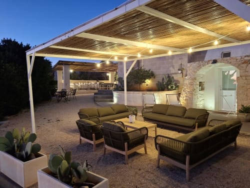 Patio serale della villa Casolare Treggi a Ostuni con zona lounge, pergolato illuminato e edificio in pietra