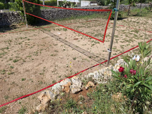 Rete da pallavolo rossa e fiori nell'area giardino della villa Casolare Treggi a Ostuni, Italia