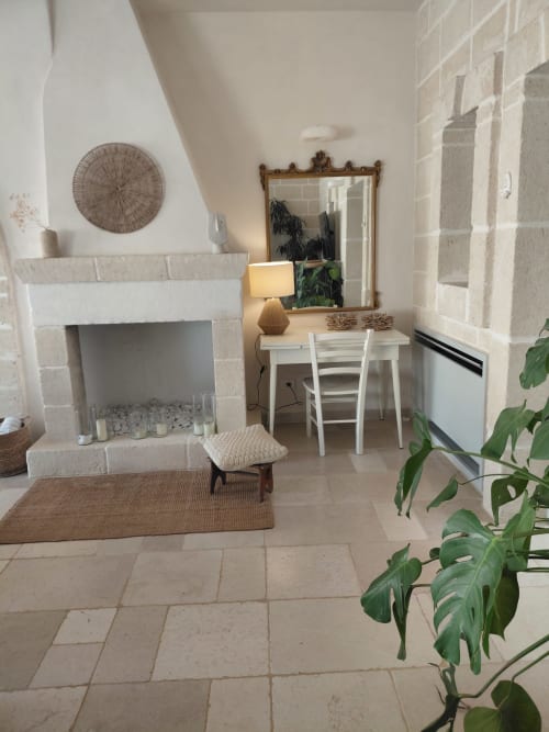 Luminoso soggiorno di Villa Casolare Treggì a Ostuni, con camino, scrivania, specchio, piante e pavimenti in cotto
