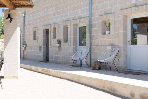 Terrazza della villa moderna di Casolare Treggi a Ostuni con sedute contemporanee, cactus in vaso e dettagli architettonici in pietra
