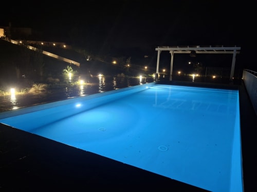 Piscina illuminata di blu nella notte con pergolato, villa Casolare Treggi a Ostuni, Italia