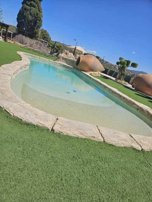 Piscina privada turquesa con terraza de piedra y jardín verde en villa Masias Can Trabal, Olèrdola, España