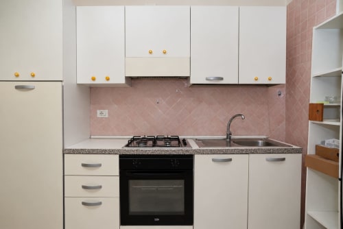 Cucina moderna negli Appartamenti Sidra, Bari con mobili bianchi, backsplash in piastrelle rosa, fornello a gas e lavello in acciaio inossidabile