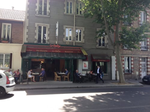 Le Dellys, bar-brasserie restaurant à Colombes : façade couverte de lierre et terrasse extérieure