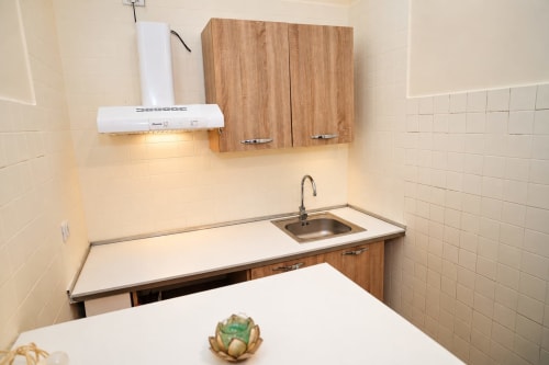 Angolo cucina compatto agli Sidra Apartments Bari con piastrelle bianche, mobili in legno, lavello in acciaio inox e design moderno