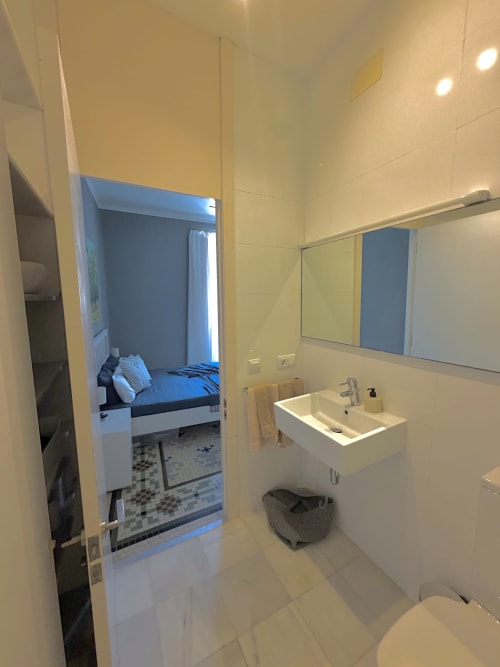 Baño moderno en apartamento de lujo en Stay Gest, Valencia con lavabo, espejo y vista al dormitorio