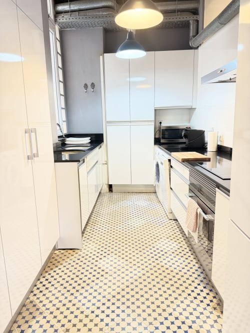 Cocina tipo galería moderna en el apartamento Stay Gest de Valencia con muebles blancos, encimeras negras y electrodomésticos de acero inoxidable