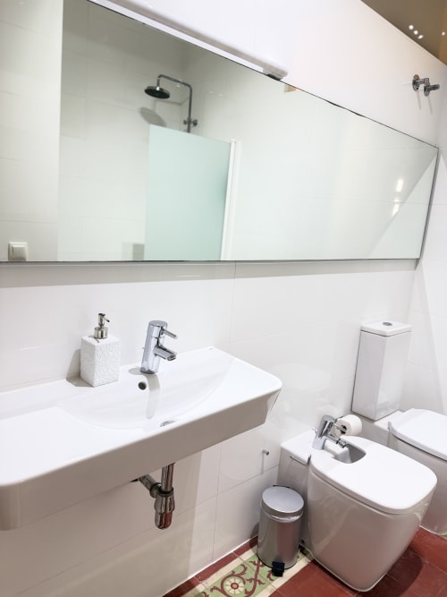 Baño moderno del apartamento Stay Gest en Valencia con lavabo blanco, inodoro, espejo y ducha con azulejos
