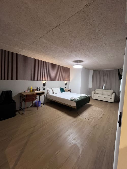 Modern suite at Hostal Abacoa in Alicante with bed, desk, sofa, wooden flooring, and contemporary furnishings