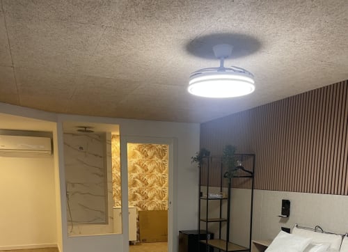 Suite del Hostal Abacoa en Alicante con iluminación moderna, zona de dormitorio, baño y salón amueblado