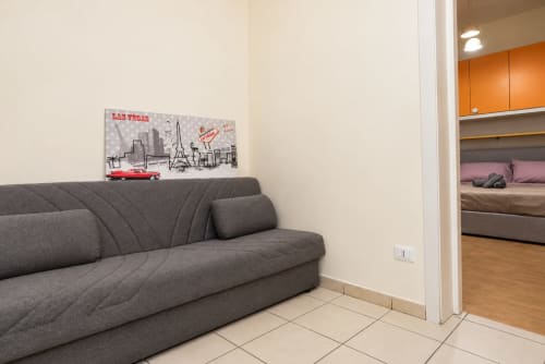 Divano grigio nel soggiorno di Sidra Apartments Bari con arte murale Las Vegas e vista della camera