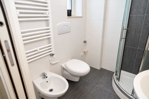 Bagno moderno negli Sidra Apartments di Bari con toilette, bidet, lavabo, scaldasalviette e pavimentazione in piastrelle scure