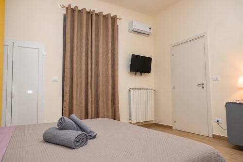 Camera moderna a Sidra Apartments Bari con letto matrimoniale, asciugamani grigi, TV a parete, climatizzatore e vista città