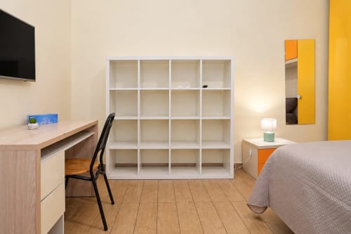 Camera Sidra Apartments Bari con scrivania in legno, mensole bianche, letto e porte accent gialle