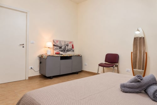 Camera da letto Sidra Apartments a Bari con letto, comò grigio, poltrona e quadri con vista sulla città