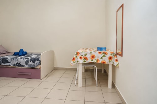 Camera Sidra Apartments a Bari con letto, tavolino con tovaglia girasoli, sedia e specchio