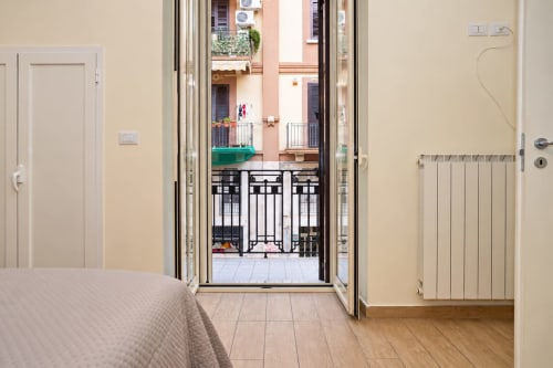 Camera da letto in Sidra Apartments Bari con porte aperte che si affacciano sul balcone e sulla città