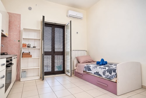 Monolocale moderno a Sidra Apartments, Bari con letto rosa, cucina, porte balconate e aria condizionata