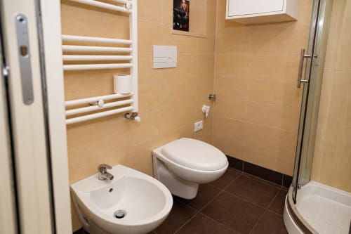 Bagno moderno di Sidra Apartments a Bari con sanitari bianchi, piastrelle beige, scaldasalviette e box doccia