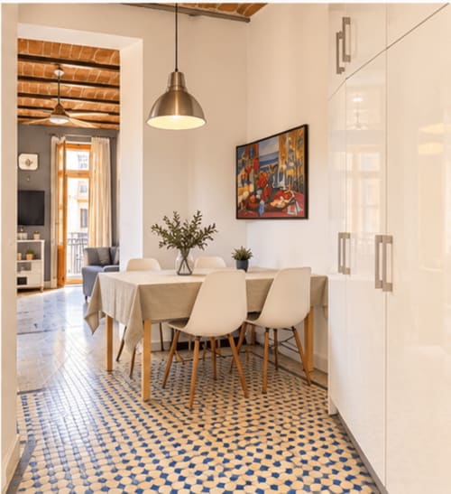 Elegante comedor en apartamento de Valencia con suelo de motivos, mesa de madera, iluminación colgante y acceso a vistas de la ciudad