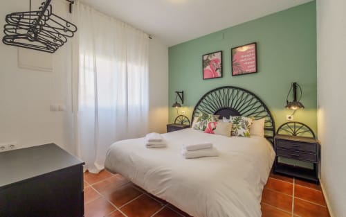 Dormitorio luminoso en villa Masia Alt de Masias Can Trabal con paredes verdes, cabecero decorativo, ropa de cama blanca y terracota