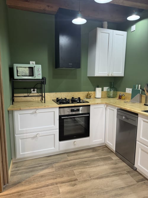Cocina moderna de la casita Cal Boix en Alberga Turisme, Berga, con muebles blancos, encimeras de madera, estufa de gas y detalles verdes