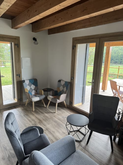 Acogedora sala moderna de Cal Boix, Berga, con vigas de madera, sillas estampadas y vistas a la montaña a través de puertas de cristal
