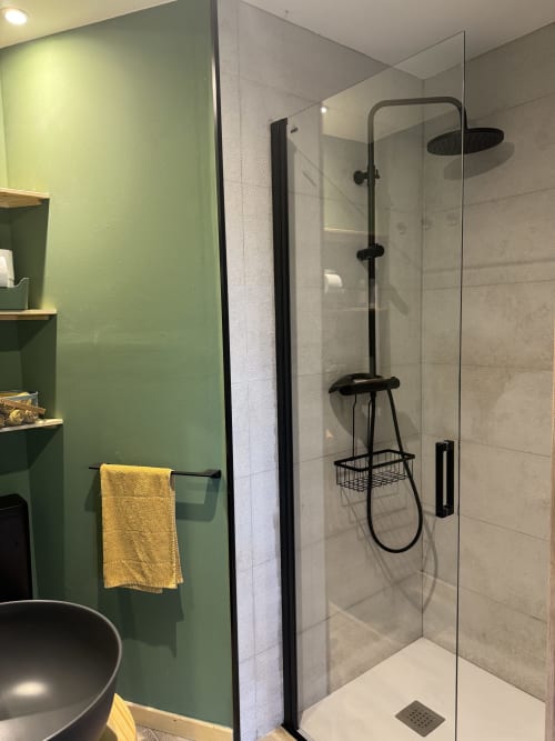 Moderno baño de la casita Cal Boix en Alberga Turisme con mampara de ducha de cristal y accesorios negros, Berga