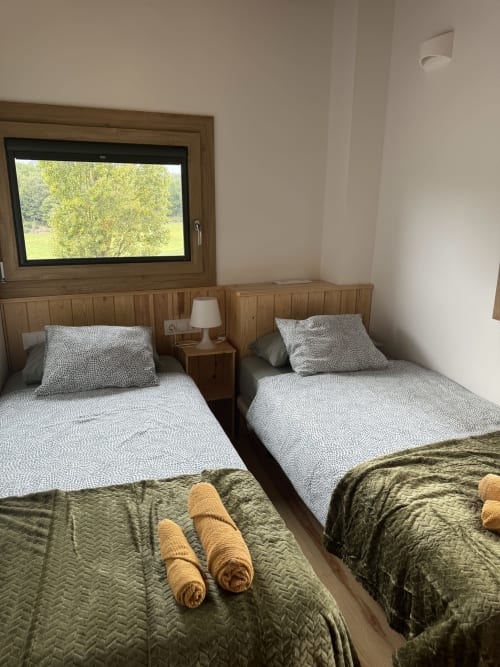 Dormitorio doble en la casita Cal Boix de Berga con camas de madera, vistas a la montaña por la ventana y decoración tradicional