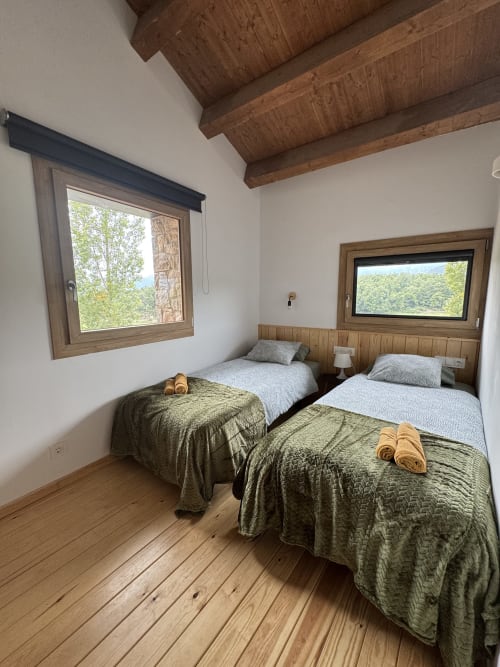 Dormitorio de la casa rural Cal Boix en Berga con camas gemelas, vigas de madera, vistas a la montaña y decoración tradicional