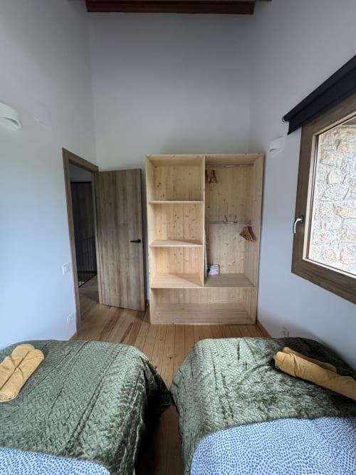 Habitación de la cabaña Cal Boix en Berga con dos camas, armario de madera y vistas a la montaña