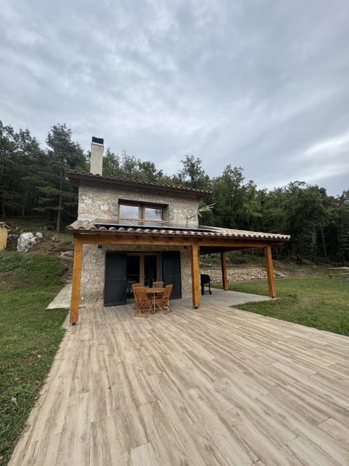 Casa rural Cal Boix en Berga con terraza de madera, fachada de piedra y vistas a las montañas rodeada de árboles