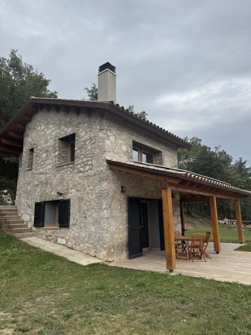 Casa de piedra Cal Boix en Berga con terraza de madera, persianas negras y vistas a la montaña