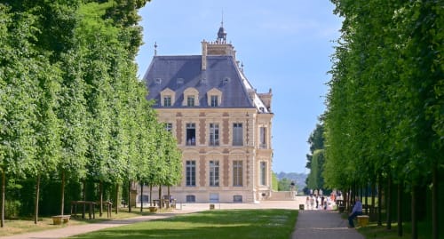 Grand château de l'Hôtel le Dellys à Colombes encadré par une avenue bordée d'arbres