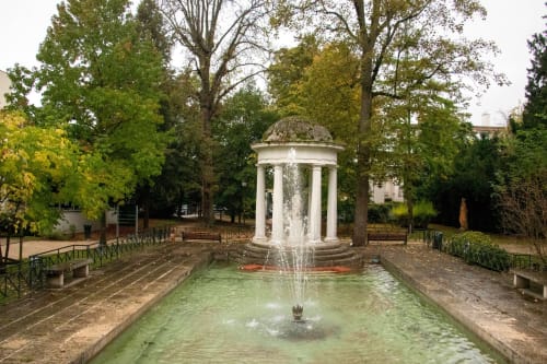 Pavillon classique avec fontaine dans le parc de l'Hôtel le Dellys à Colombes, entouré d'arbres d'automne et de bancs