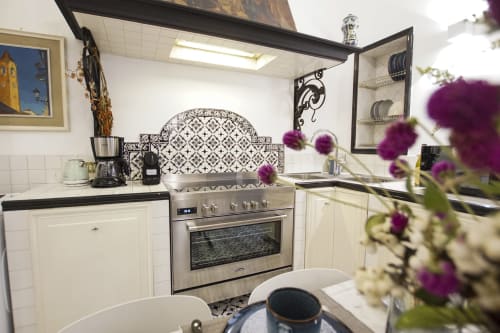 Elegante cucina nella Magna Mater Suite, Roma con mobili color crema, piano cottura acciaio inox, alzatile decorativo e viola
