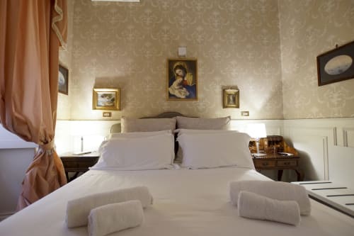 Camera da letto elegante della Suite Magna Mater, hotel Roma con biancheria bianca, opere d'arte classiche e carta da parati damascata