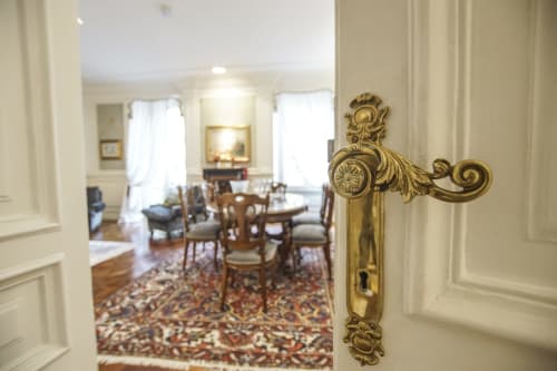 Elegante maniglia in ottone che si apre sulla raffinata sala da pranzo della Suite Magna Mater dell'hotel Roma con arredi d'epoca e decorazioni a motivi