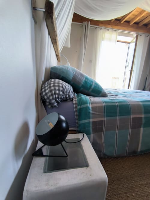 Chambre douillette à la Furanelle B&B à Saint-Étienne avec literie écossaise, lampe de bureau noire et porte vitrée ouvrant sur la vue montagne