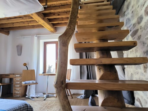 Chambre moderne avec poutres en bois, escalier en spirale, bureau et murs en pierre rustique à la Furanelle B&B à Saint Etienne