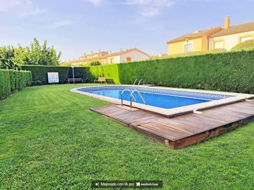 Piscina amb terrassa de fusta a la casa rural La Vela d'Estartit, envoltada de gespa verda i tanques a L'Estartit, Espanya