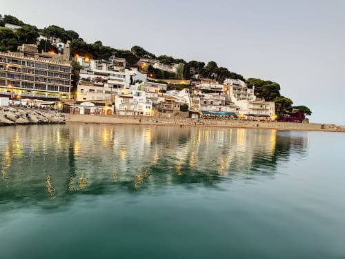 Colorful beachfront buildings in L'Estartit reflecting in turquoise Mediterranean waters