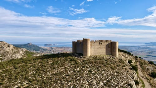 Medieval castle ruins perched on rocky hilltop in L'Estartit, Spain with Mediterranean coastline views
