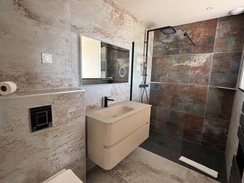 Salle de bain moderne aux Villas d'A Storia à Pinarellu avec vasque crème, douche à effet pluie et accents de carrelage rustique