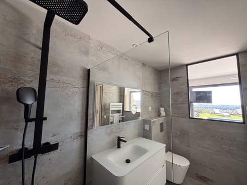 Salle de bain moderne aux Villas d'A Storia à Pinarellu avec douche pluie, lavabo blanc et fenêtre vue mer