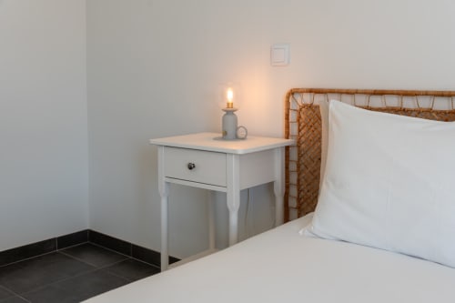 Cozy bedroom at Canhoto Douro B&B with wicker headboard, white bedding, white nightstand with lamp in São Lourenço do Douro