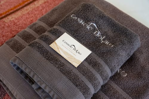 Folded gray towels with Canhoto Douro branding label at boutique B&B in São Lourenço do Douro