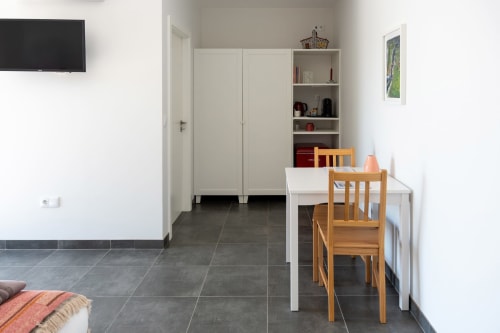 Quarto Minho at Canhoto Douro: dining area with wooden chairs, white table, shelving, and flat-screen TV in São Lourenço do