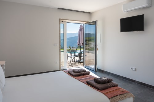 Spacious bedroom at Canhoto Douro with floor-to-ceiling doors opening to terrace with mountain views, featuring yoga mats and