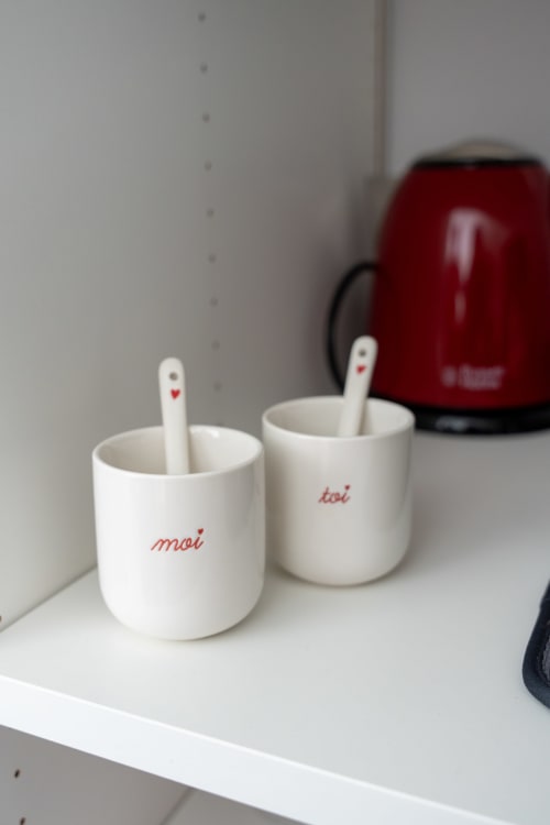 Two white ceramic mugs labeled 'moi' and 'toi' with spoons at Canhoto Douro B&B in São Lourenço do Douro, Portugal